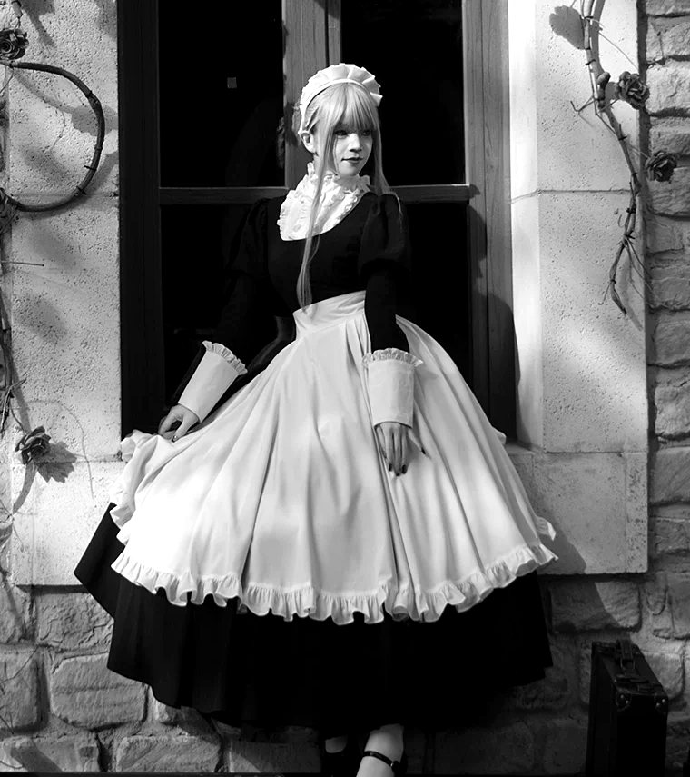Plate No. V, Katerina: a day dress with a ruffled white apron, worn by a model at a window